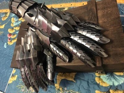Witch King metal gauntlets crossed together on gray background