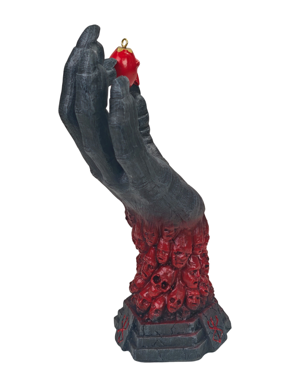 A gothic-style hanging ornament featuring a dark gray skeletal hand holding a small red apple with a gold loop, with a base of red skulls and cross motifs, isolated on a white background.